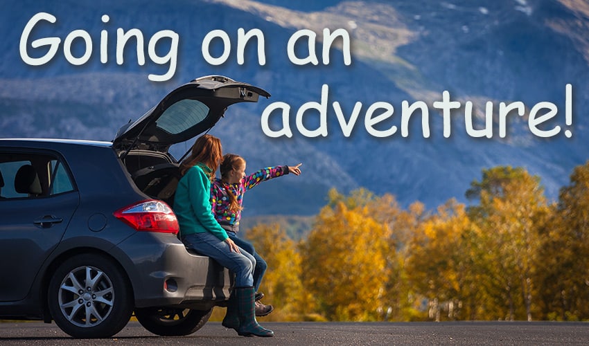 Mom and daughter sitting in back of car in mountains going on an adventure